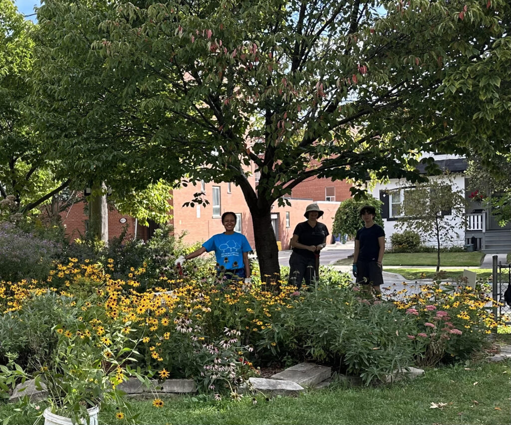 Three women posing in pollinator garden in Ben Nobleman Park Community Orchard