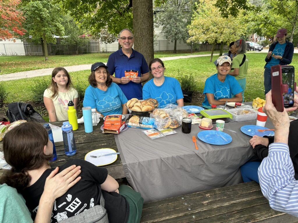 Ben Kafetz with two home depot cards standing behind the harvest table with the volunteers of the Ben Nobleman Park Community Orchard. 