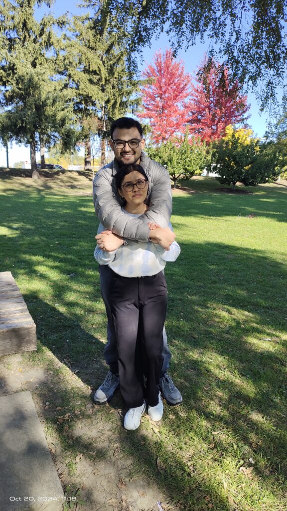 Two volunteers pose in park with trees in background