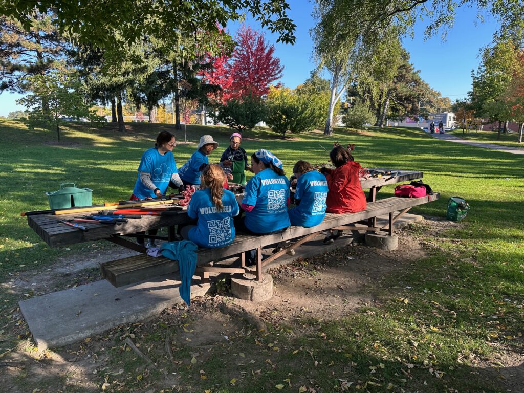 Volunteers sit at the harvest table while sharpening tools