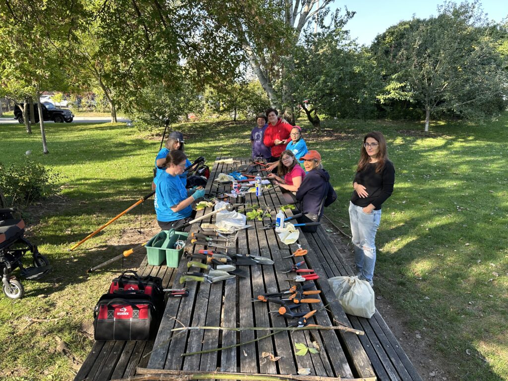 Volunteers gathered around harvest table with tools. 